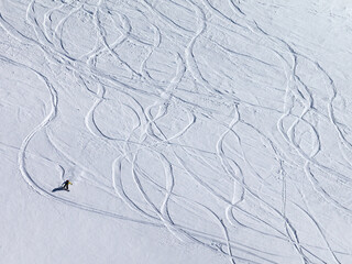 Snowboarder downhill on off piste slope with newly-fallen snow