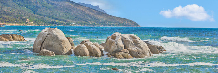 Meereslandschaft von Camps Bay Beach, Table Mountain National Park, Kapstadt, Südafrika. Ruhige malerische Meereslandschaft mit Felsen und Wellen an einem blauen Horizont. Atemberaubendes türkisfarbenes Wasser an einer Küste