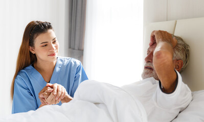 Fototapeta premium The young doctor held the hand of an old Caucasian man to take care of him. Talk to him from his illness lying in bed in his bedroom