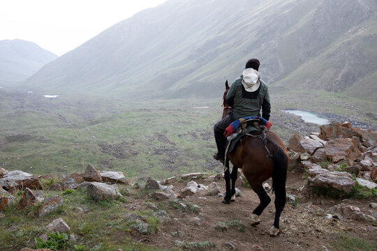 A man rides his horse on a cold, foggy day in the Tian Shan mountains of Kyrgyzstan.