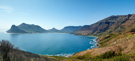Obraz premium Wide angle panorama of mountain coastline against clear blue sky in South Africa. Scenic landscape of Twelve Apostles mountain range near a calm ocean in Hout Bay. Popular hiking location from above