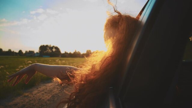 free woman hand out of window ride car wind in face. concept car travel on road. girl stretches her hand out of car window sun glare sunset. movement driver hand out of window Hand in the rays of sun