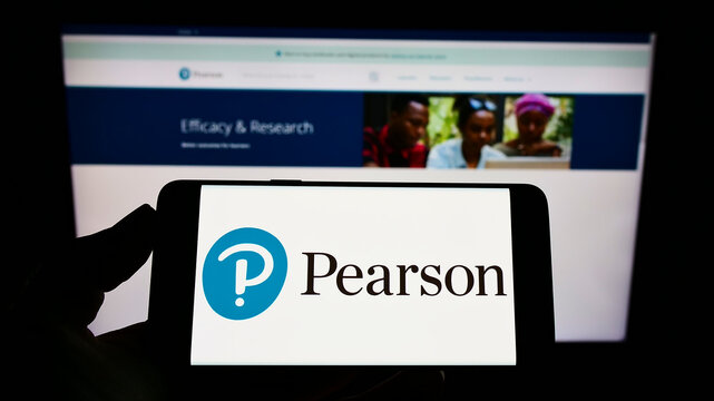 Stuttgart, Germany - 01-30-2022: Person holding mobile phone with logo of British publishing company Pearson plc on screen in front of business web page. Focus on phone display.