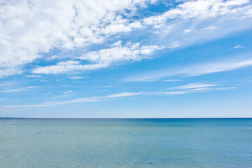 Copy space at sea with a cloudy blue sky background. Calm water surface across an empty ocean across the horizon. Scenic and tranquil seascape panorama view for a peaceful summer getaway in nature