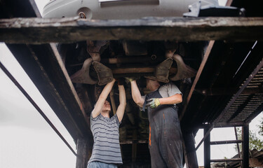 Obraz na płótnie Canvas two auto mechanics repairing a car, teamwork.