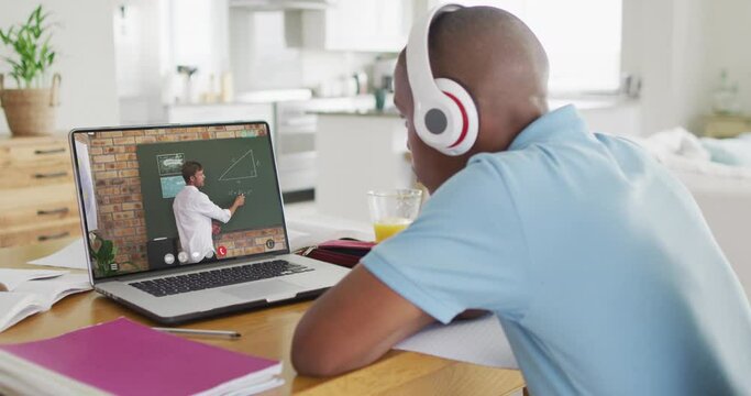 African american teenage boy using laptop for video call, with male teacher on screen