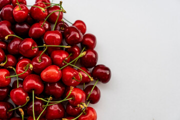 Pile of cherries with stalks on white background with copy space. Sweet red cherries. Top view. Selective focus.