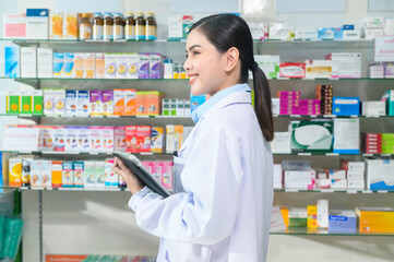 Portrait of female pharmacist using tablet in a modern pharmacy drugstore.