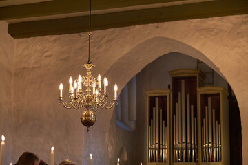 Old fashioned brass chandelier with candle light bulbs hanging from roof or ceiling in a historic...