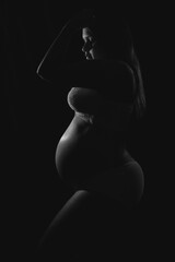 Pregnant woman silhouette low key, black background