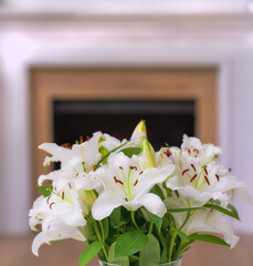 Closeup of a bouquet of lily flowers in a vase on a table at home. Bunch of white Lilium flowering plants blooming in a jar in the living room. Lilies on display in a vessel in the lounge in a house