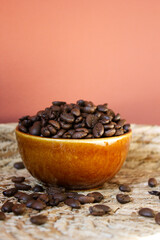 roasted coffee beans in a brown ceramic bowl on a table in natural design in vertical format with space for text