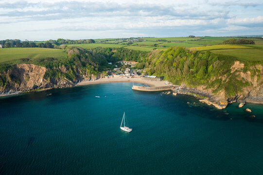 Aerial view of Yacht anchored in Polkerris harbour with view of harbour, beach and surrounding countryside, Par, Polkerris, Cornwall, United Kingdom.