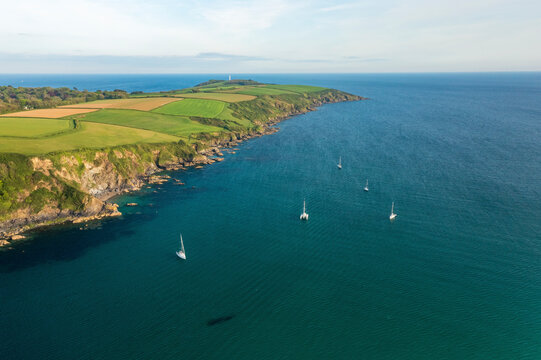 Aerial view of Yacht anchored in Polkerris harbour with view of harbour, beach and surrounding countryside, Par, Polkerris, Cornwall, United Kingdom.