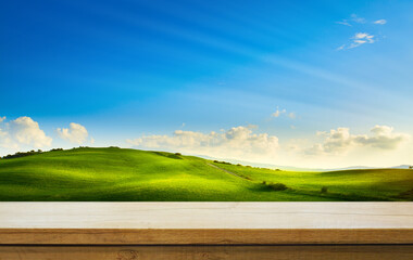 Art Empty wooden table on green farm field background. Mockup for countryside outdoor product...