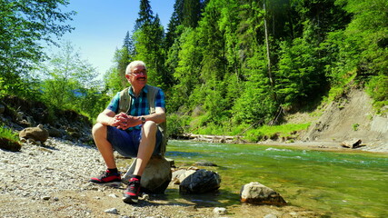 aktiver älterer Mann beobachtet glücklich den Fluss Ammer im sonnigen Naturschutzgebiet...
