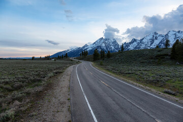 Scenic Road surrounded by Mountains and Trees in American Landscape. Spring Season. Grand Teton National Park. Wyoming, United States. Nature Background.