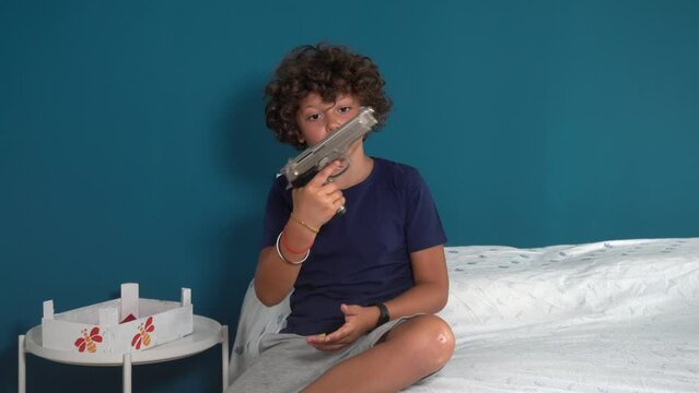 8-year-old boy alone at home finds a real gun in his parents' drawer - in America more and more children find guns in domestic places - social danger and violence