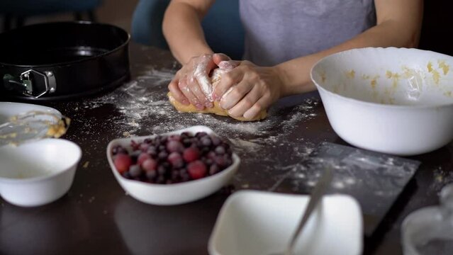 Closeup shot of hands applying flour on dough, woman kneading dough, making pie using traditional recipe