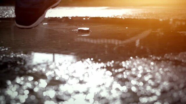 Trail runners run in a shallow river at sunset. Active athletes have morning runs in shallow water, male runners jogging, splashing water at sunrise, Footage SUPER SLOW MOTION, CLOSE UP,