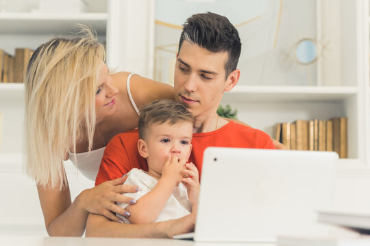 young couple watching something in the laptop with their little son, medium closeup indoor family concept. High quality photo
