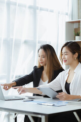 Atmosphere in the office of a startup company, two female employees are discussing, brainstorming ideas to working on summaries and marketing plans to increase sales and prepare reports to managers.