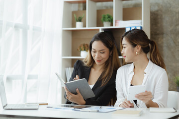 Atmosphere in the office of a startup company, two female employees are discussing, brainstorming ideas to working on summaries and marketing plans to increase sales and prepare reports to managers.