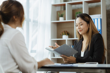 Atmosphere in the office of a startup company, two female employees are discussing, brainstorming ideas to working on summaries and marketing plans to increase sales and prepare reports to managers.