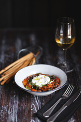 Appetizing dish on a dark wooden table. Vegetable stew with egg.