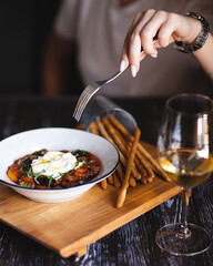 Appetizing dish on a dark wooden table. Vegetable stew with egg.