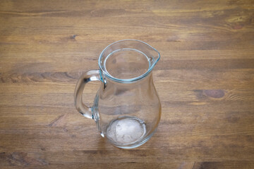 Empty glass pitcher close up on wooden table with copy space