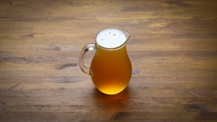 Full pitcher of beer close up on wooden table with copy space