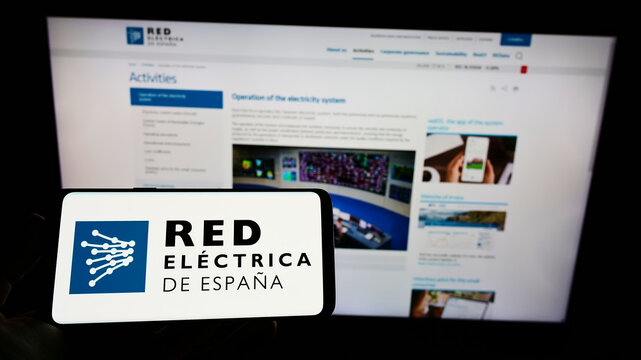 Stuttgart, Germany - 01-30-2022: Person holding smartphone with logo of Spanish energy company Red Electrica de Espana on screen in front of website. Focus on phone display.