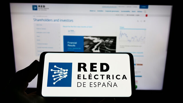 Stuttgart, Germany - 01-30-2022: Person holding cellphone with logo of Spanish energy company Red Electrica de Espana on screen in front of webpage. Focus on phone display.