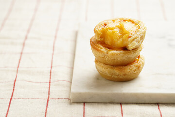 Traditional portuguese vanilla pudding puff pastry pastel de nata stacked on each other on marble...