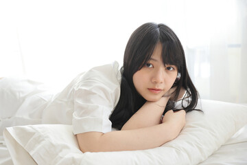 Beautiful young woman waking up in the morning at white bedroom