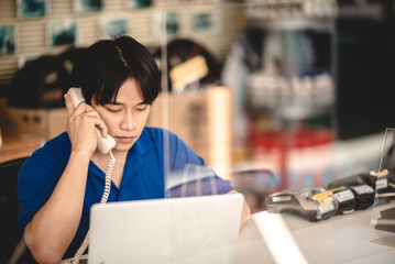 Young male worker focused on working on laptop in a car shop with NFC payment machine on desk to receive card payment