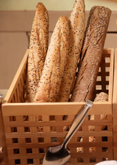 Mehrere Brote, Baguette stehen hochkannt im Holzkorb.
