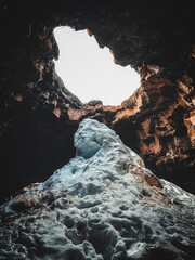 Volcanic Crater at the End of a Lava Tunnel. Other worldly view of a snow and ice formation at the...