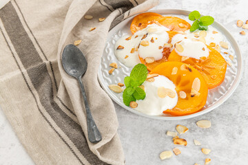 Sliced persimmon with yogurt and almonds. Healthy food concept on light background. top view