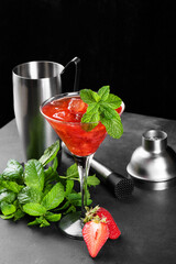 Cold summer strawberry cocktail mojito, margarita, daiquiri in a martini glass on dark background with bartender set