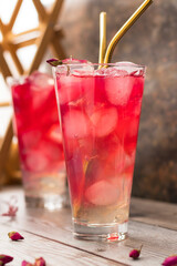 Summer cold lemonade with rose syrup in transparent glasses and golden cocktail tubes. Refreshing homemade drink ovshala. vertical position.