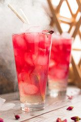 Refreshing homemade drink ovshala. Summer cold lemonade with rose syrup in transparent glasses and golden cocktail tubes. vertical position.