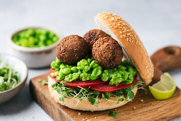 Plant based falafel burger with vegan green pea sauce and tomatoes. Vegan falafel sandwich