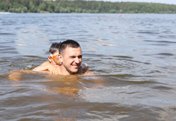 father and son swim together in a river pond