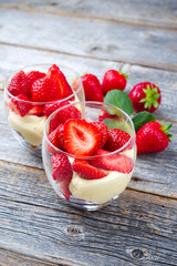 Traditionelle italienische Mascarpone Creme mit Vanille Quark und frischen Erdbeeren serviert als close-up in einem Glas auf einem rustikalen Holz Board 
