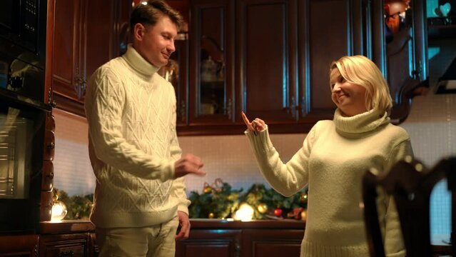 Couple making pinky swear making peace after quarrel at home indoors. Smiling loving Caucasian man and woman shaking little fingers hugging standing in kitchen. Conflicts solution