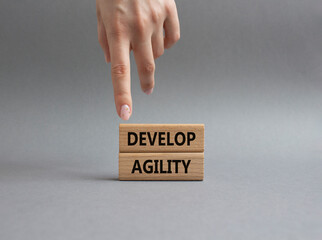 Develop agility symbol. Concept word Develop agility on wooden blocks. Beautiful grey background....