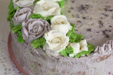 Lavender cake decorated with cream flowers. Close-up.