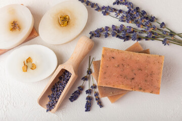 Obraz na płótnie Canvas Natural lavender soap with lavender flowers on white cement background.Handmade Soap.Cosmetic product with essential oils.spa product.Space for text. Flat lay.